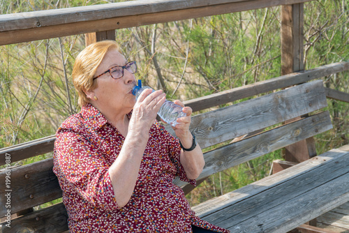 Senior woman drinking water from a plastic bottle outdoors