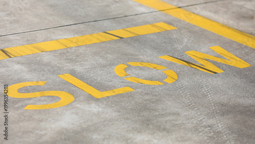 Fotografie Yellow slow road marking painted on gray asphalt surface, indicating traffic saf