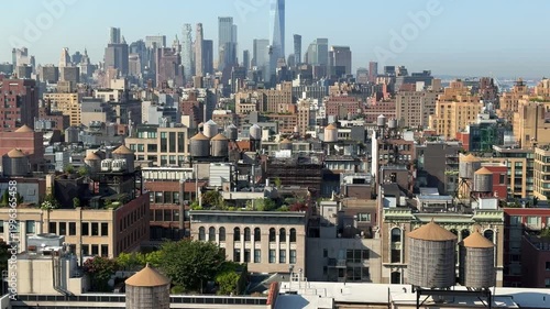 This wide shot captures the dense New York City skyline with its signature rooftop water towers and modern glass skyscrapers. One World Trade Center stands as the central landmark above the bustling