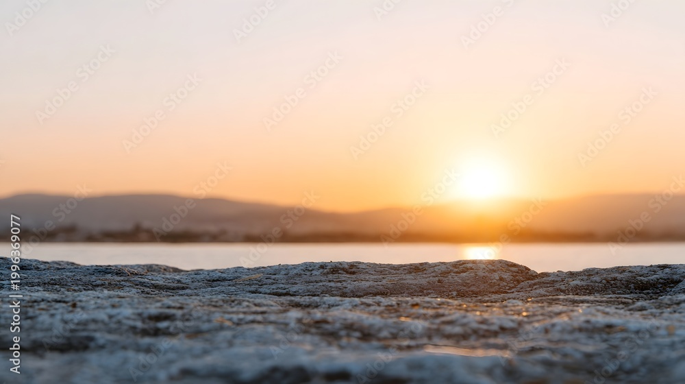 Naklejka premium Golden hour sunlight illuminates a textured natural surface against a soft diffused horizon at sunrise or sunset