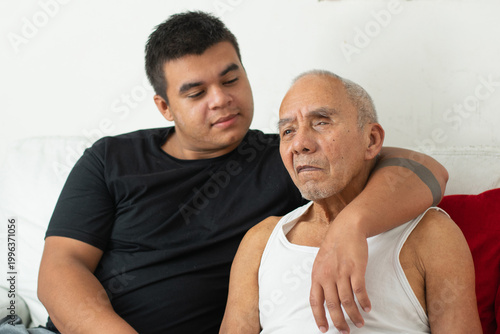 Young man with arm around elderly father showing affection and emotional family support