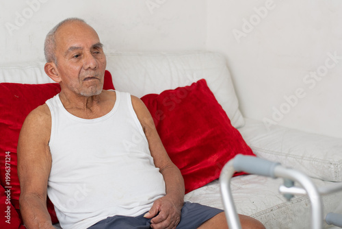 Elderly man sitting on couch with red pillows resting comfortably in home environment