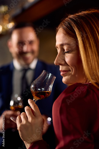 Schilderij op canvas Smiling woman tasting cognac while drinking in bar.