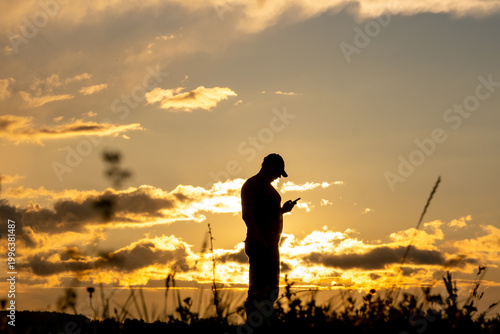 Fotografi Man against the backdrop of the sunset sky in a field