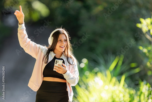 Foto Young woman enjoying music outdoors raising hand