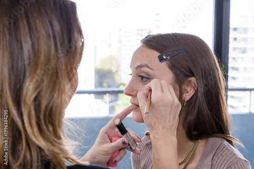Make-up artist working in his studio applying makeup to a beautiful young girl