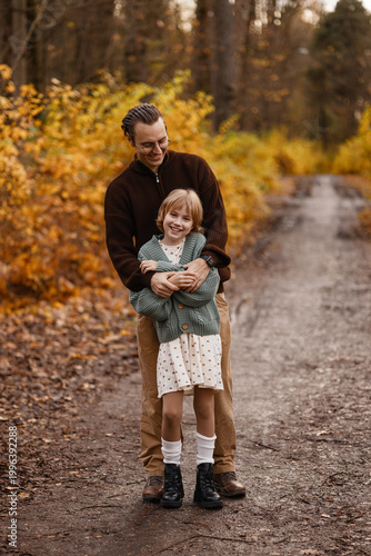 Father Hugging Daughter In Warm Embrace On Muddy Trail With Smiling Faces And Cozy Layers, Intimate Protective Moment Surrounded By Autumn Foliage And Soft Light Conveying Safety And Deep