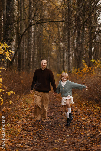 Father And Daughter Running Together On Forest Trail Laughing And Full Of Energy With Leaves Kicking Up Around Boots And Cozy Layers, Candid Lifestyle Scene Capturing Motion, Momentum