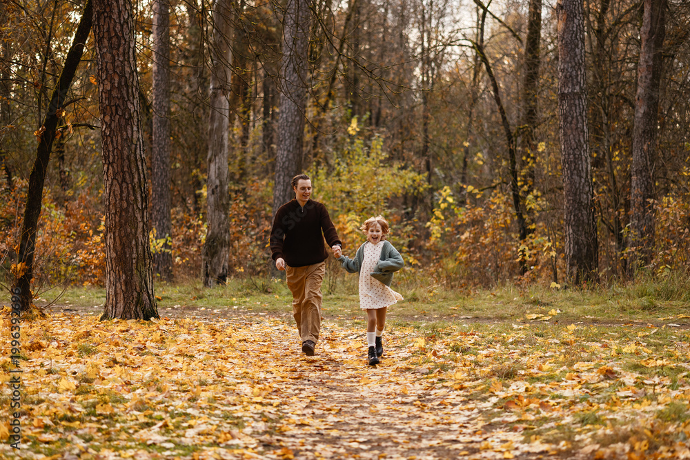 Fototapeta premium Father And Daughter Running Side By Side Down Leafy Path, Carefree Laughter And Energetic Stride With Windtossed Hair And Playful Momentum Among Amber Foliage Capturing Spontaneous Family