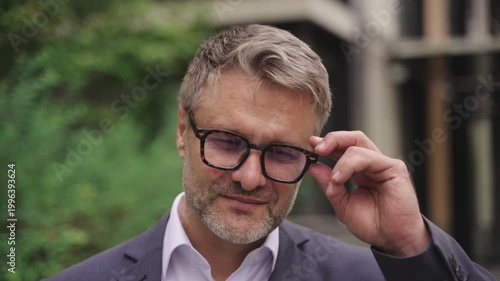 Smiling businessman taking off the glasses while posing at camera. Real time concept