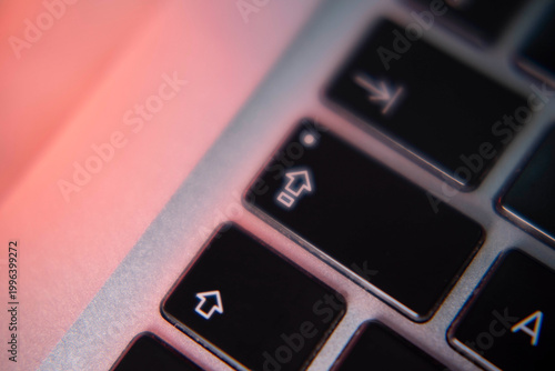 Macro detail of laptop keyboard under warm lighting, highlighting texture, contrast and modern workspace aesthetics with a minimalist visual approach.
