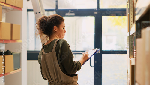 Φωτογραφία Young person inspecting supplies list on papers, reviewing quality control report to ship orders