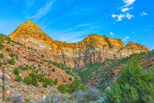 Slika na platnu A low-angle view of massive monolithic sandstone rock formations rising sharply against a bright blue sky in Zion National Park