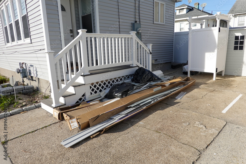 Φωτογραφία Trash and extra siding in a pile by steps going to a house