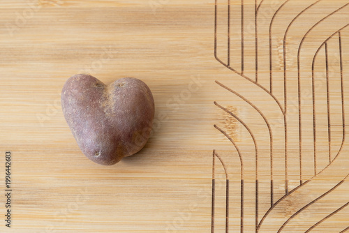 heart-shaped potato on a wooden cutting board, connecting love and food and home cooking.
