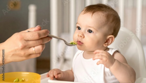 Adorable baby being fed healthy pureed food on a spoon