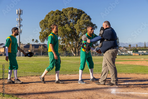 Post-game catcher shaking hands with umpire as baseball team walking off animated score above plate