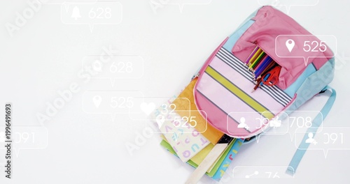 Showing pastel backpack holding ABC supplies, notebook on white table with social pins, copy space