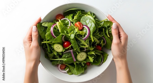 Top view of hands holding a bowl of fresh mixed green salad on white background