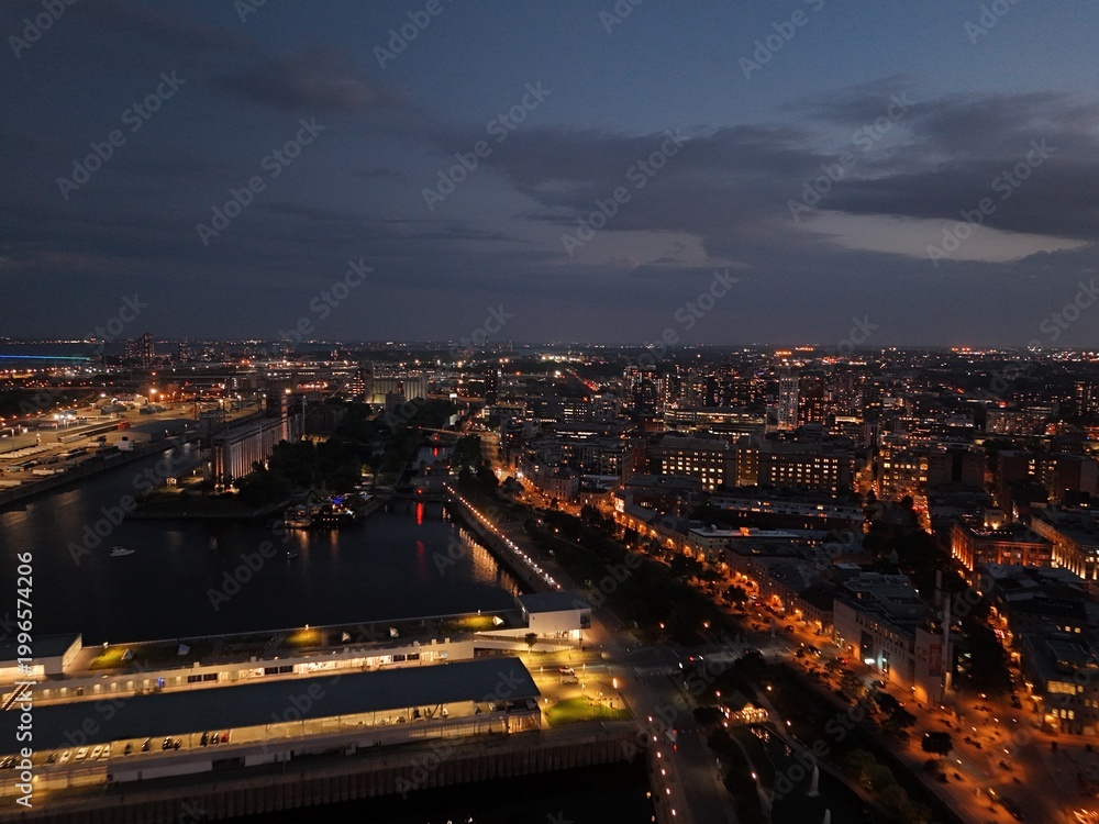 Fototapeta premium Montreal skyline at sunset with Old Port clock tower, marina and city lights reflecting on water. g.