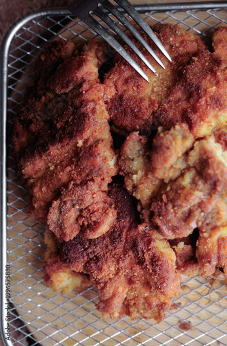Milanesas de pollo pescado o camarones empanizados o carne de res en una rejilla de aluminio con un tenedor al lado, vista aerea cenital con acercamiento o macro.
