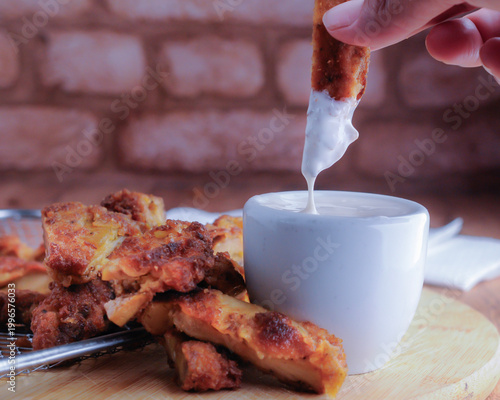 Milanesas de pollo pescado o camarones empanizados con un tazoncito de ranch o gravy para sazonar, sobre una tabla de cortar de madera