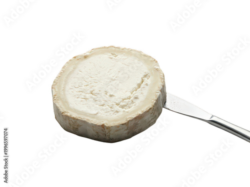 Obraz na plátne Fresh round goat cheese slice with a white bloomy rind on a silver knife isolate