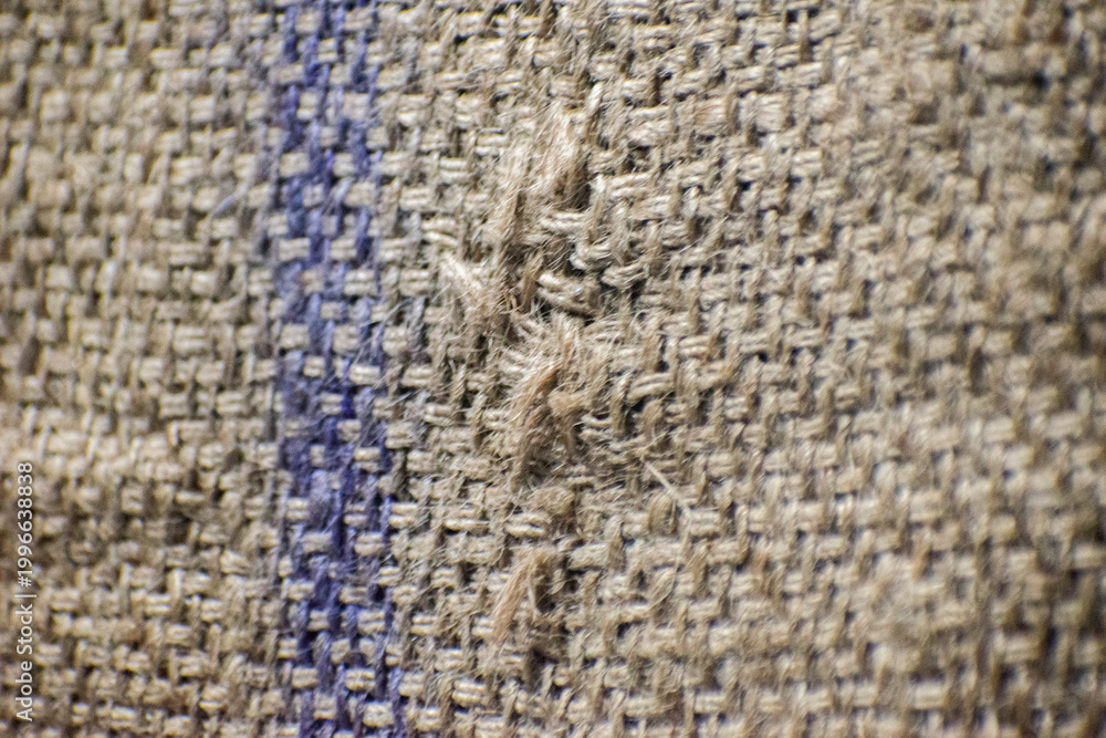 Fototapeta premium Close up of frayed burlap sack texture with blue stripe and rustic jute fabric.