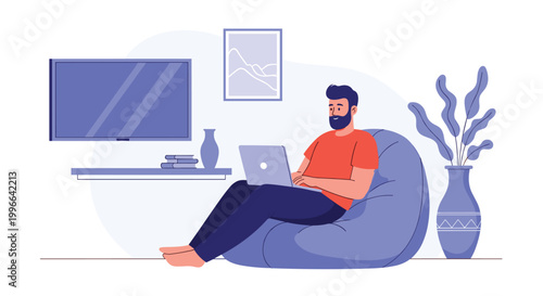 Young bearded man sitting in a blue bean bag chair in a living room while focusing on his work on a silver laptop computer.