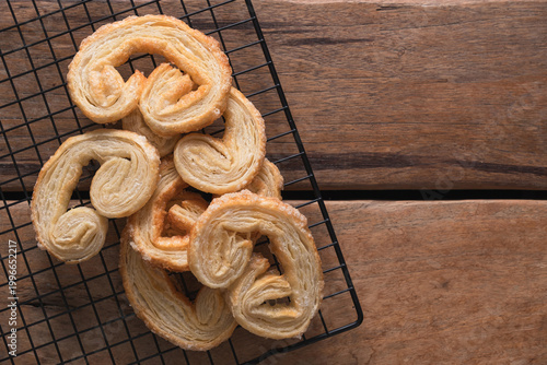 Freshly baked Palmiers on a black cooling rack over a rustic wooden table.
