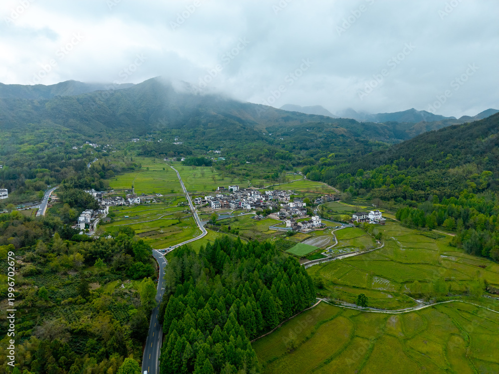 Fototapeta premium An aerial view shows the traditional houses of the ancient Hongcun Village located in Yixian County of Anhui Province in China surrounded by lush green mountains and scenic agricultural fields