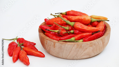 Red cayenne pepper (cabe rawit merah) on wooden bowl isolated on white background	