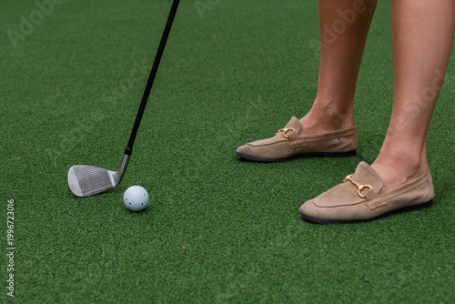 Close-up of woman putting golf ball near hole on putting green
