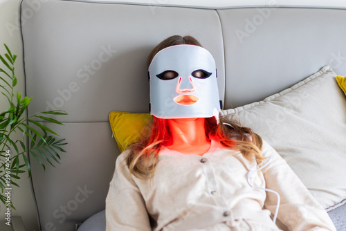 Woman using LED light therapy mask at home