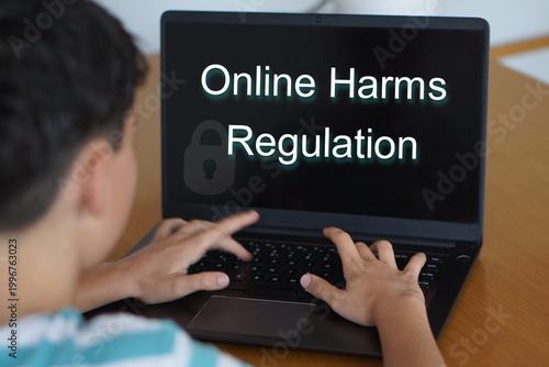 Online harms regulation. Teenager typing on his laptop
