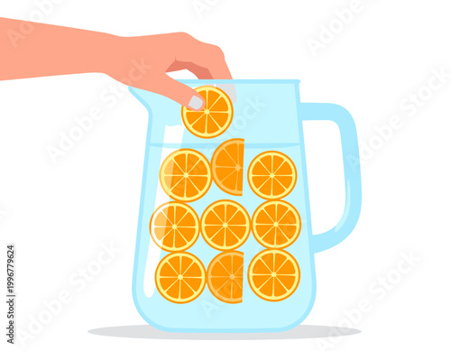 A hand placing a fresh orange slice into a clear pitcher filled with water and more orange slices, preparing a refreshing drink.