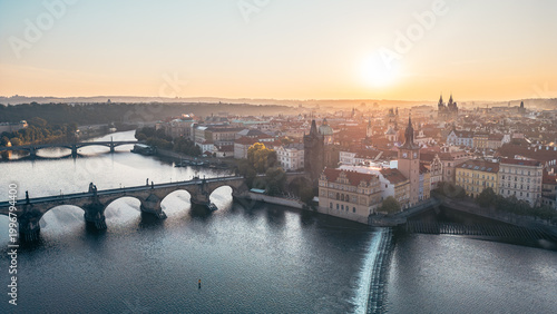 фотографія The early morning sun casts a golden glow over Charles Bridge and the Old Town Bridge Tower, highlighting the beauty of Prague and the Vltava River below