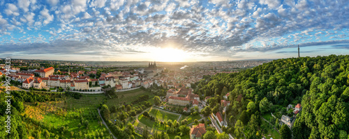 Schilderij op canvas Golden sunlight breaks over Prague, illuminating the city historic architecture and lush greenery