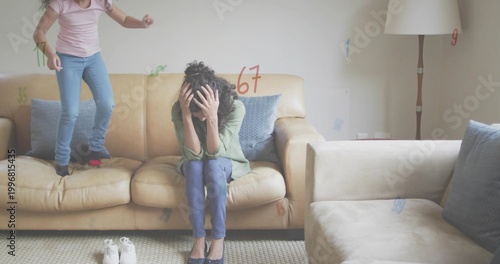 Foto Covering face woman in green top while girl bouncing on living room sofa, white