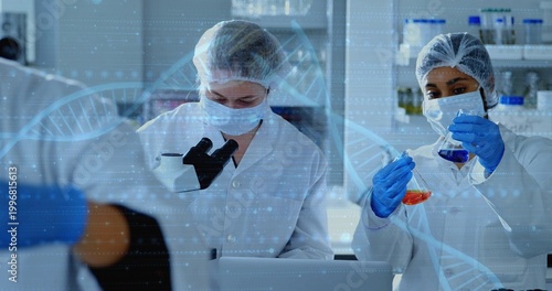 Canvastavla Examining microscope two scientists wearing PPE comparing orange, blue flasks at