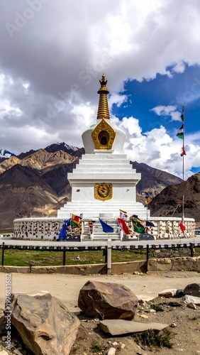 White tiered Buddhist sanctuary against mountain backdrop, flags waving
