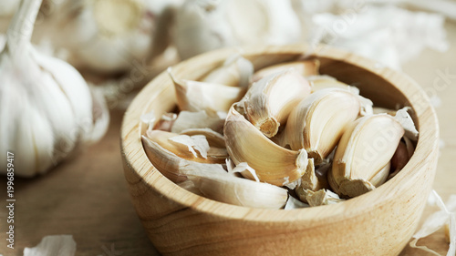 Close up garlic in wooden bowl with sunlight from window highlighting texture and creating warm kitchen mood