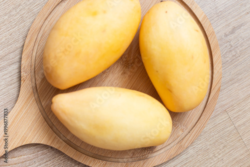 Fresh yellow picked mangoes displayed on wooden board