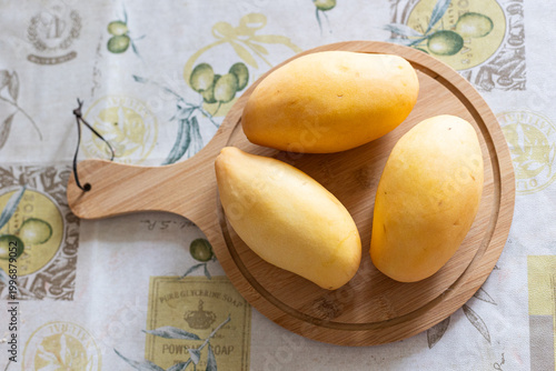 Fresh yellow picked mangoes displayed on wooden board