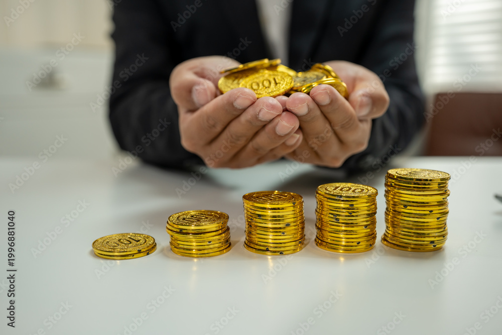 Fototapeta premium Businessman calculating rising costs with gold coins, inflation and financial growth concept.