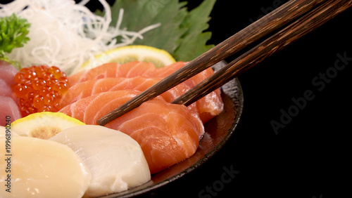 Photos Wooden Chopsticks Picking Up Fresh Salmon Sashimi From a Sushi Platter