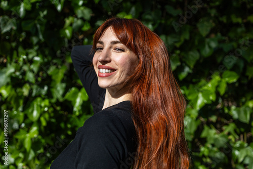 Portrait of a smiling redheaded woman against a green background.