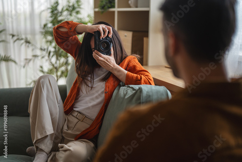 Woman capturing portrait with vintage camera indoors