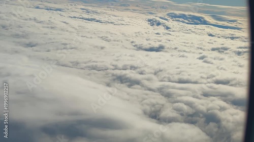 Aerial Clouds Viewed Through Airplane Window, Gentle Lateral Pan Across Layered Cloud Blanket, Soft Golden Hour Light, Tranquil Atmosphere, Subtle Cabin Frame Vignette, Ideal For Travel Footage,