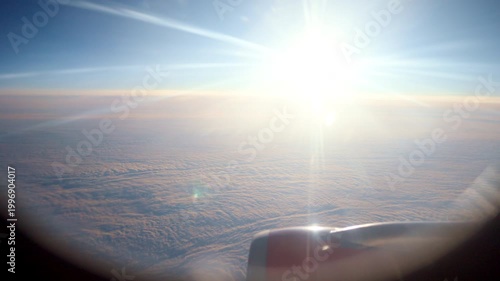 Airplane Window Bright Sun Over Clouds, Engine Reflected In Glass, Intense Lens Flare, Highaltitude Blue Sky, Thin Contrails, Panoramic Horizon, Tranquil Travel Atmosphere